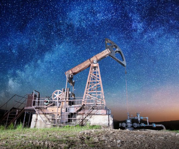 Oil industry equipment pumping crude oil in the night under Milky way